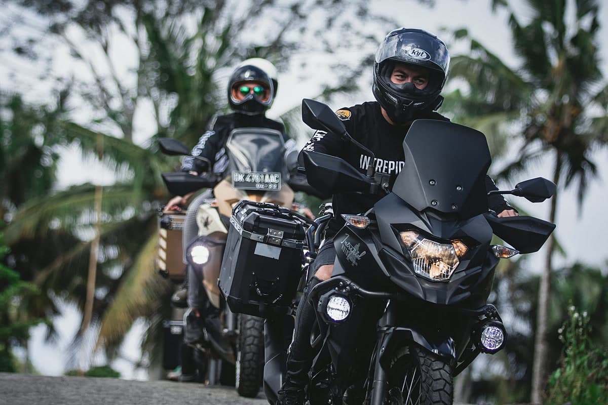 Two motorcycle riders on a forested Bali road